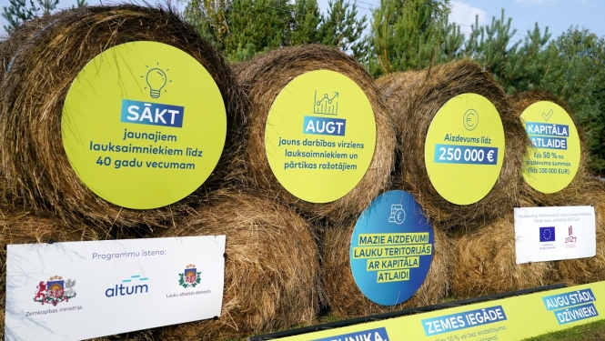 Siena ruļļi, kuru galos piestiprinātas apaļas reklāmas plāksnes par aizdevumu programmu