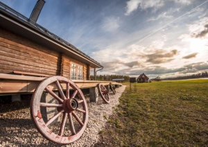 Lauku ēkas sāns ar pieslietu koka ratu riteni