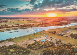Skats no drona saulrietā uz saimniecību un daugavu
