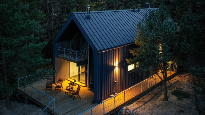 Brūna divstāvīga viesu māja ar gaismu logos no drona skata