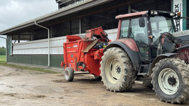 Traktors ar maisītāju novietots pie saimniecības ēkas