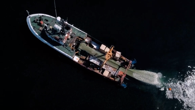 Zvejas laiva no augšas ar tīklu zvejo jūrā