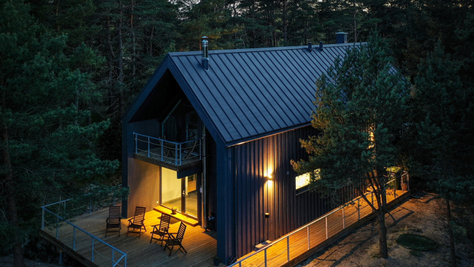 Brūna divstāvīga viesu māja ar gaismu logos no drona skata