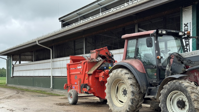 Traktors ar maisītāju novietots pie saimniecības ēkas