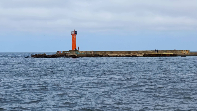 Sarkana bāka uz mola gala jūrā