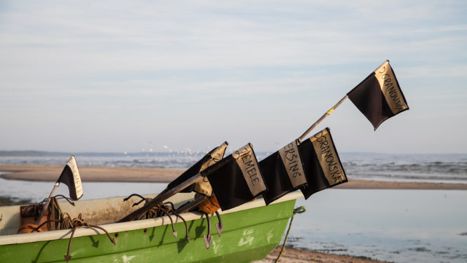 Zvejas laiva ar tīklu karogiem jūrmalā