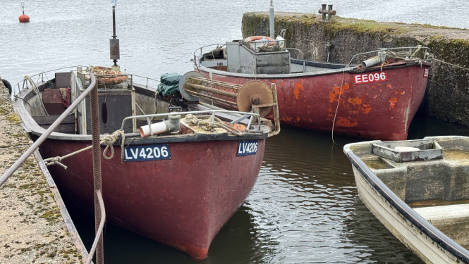 Divas sarkanas zvejas laivas piesietas ostā