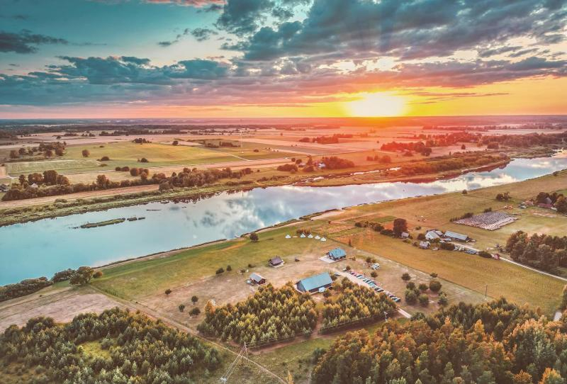 Skats no drona saulrietā uz saimniecību un daugavu