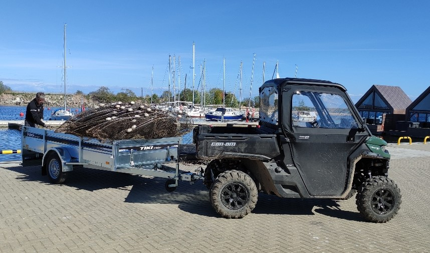 Kvadracikls ar piekabi, kurā salikti zvejas tīkli