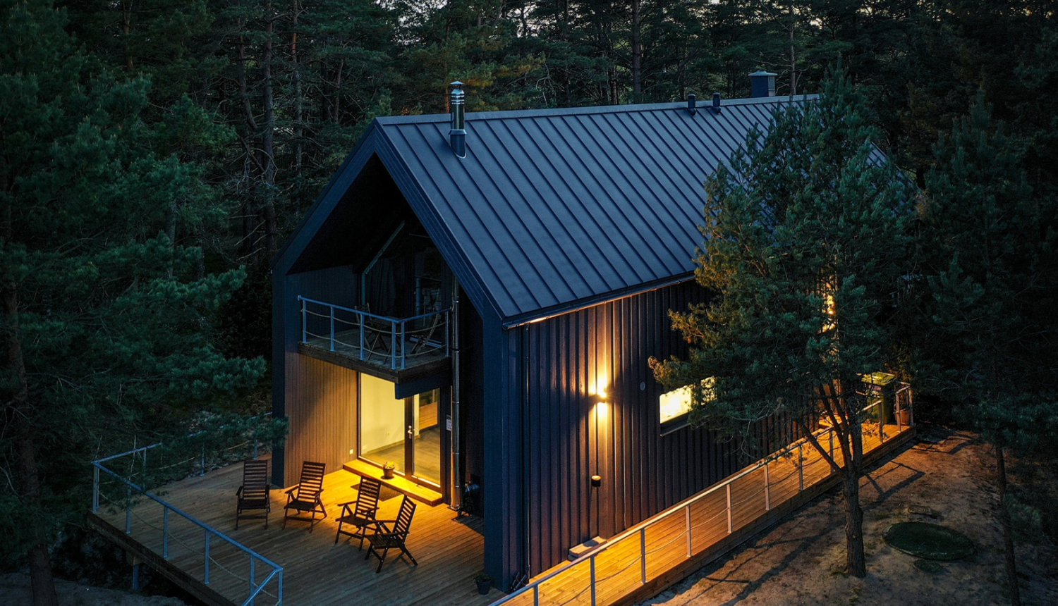 Brūna divstāvīga viesu māja ar gaismu logos no drona skata