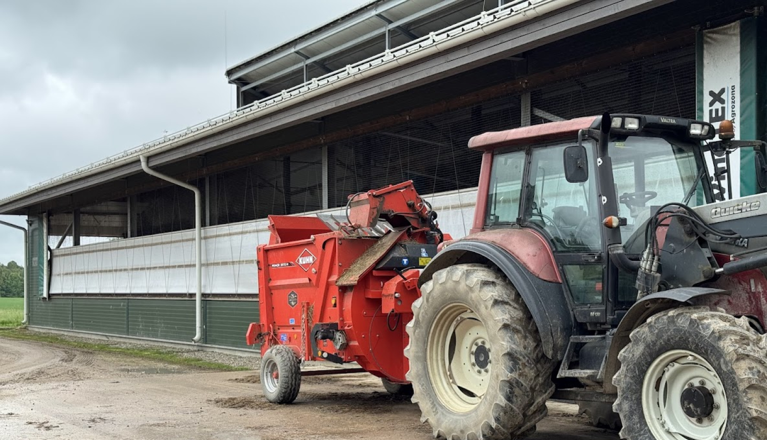 Traktors ar maisītāju novietots pie saimniecības ēkas