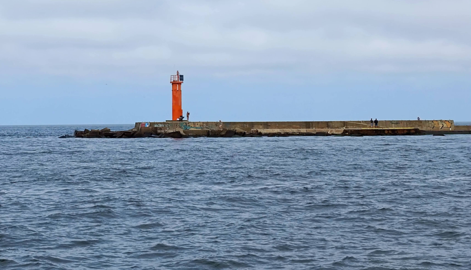 Sarkana bāka uz mola gala jūrā