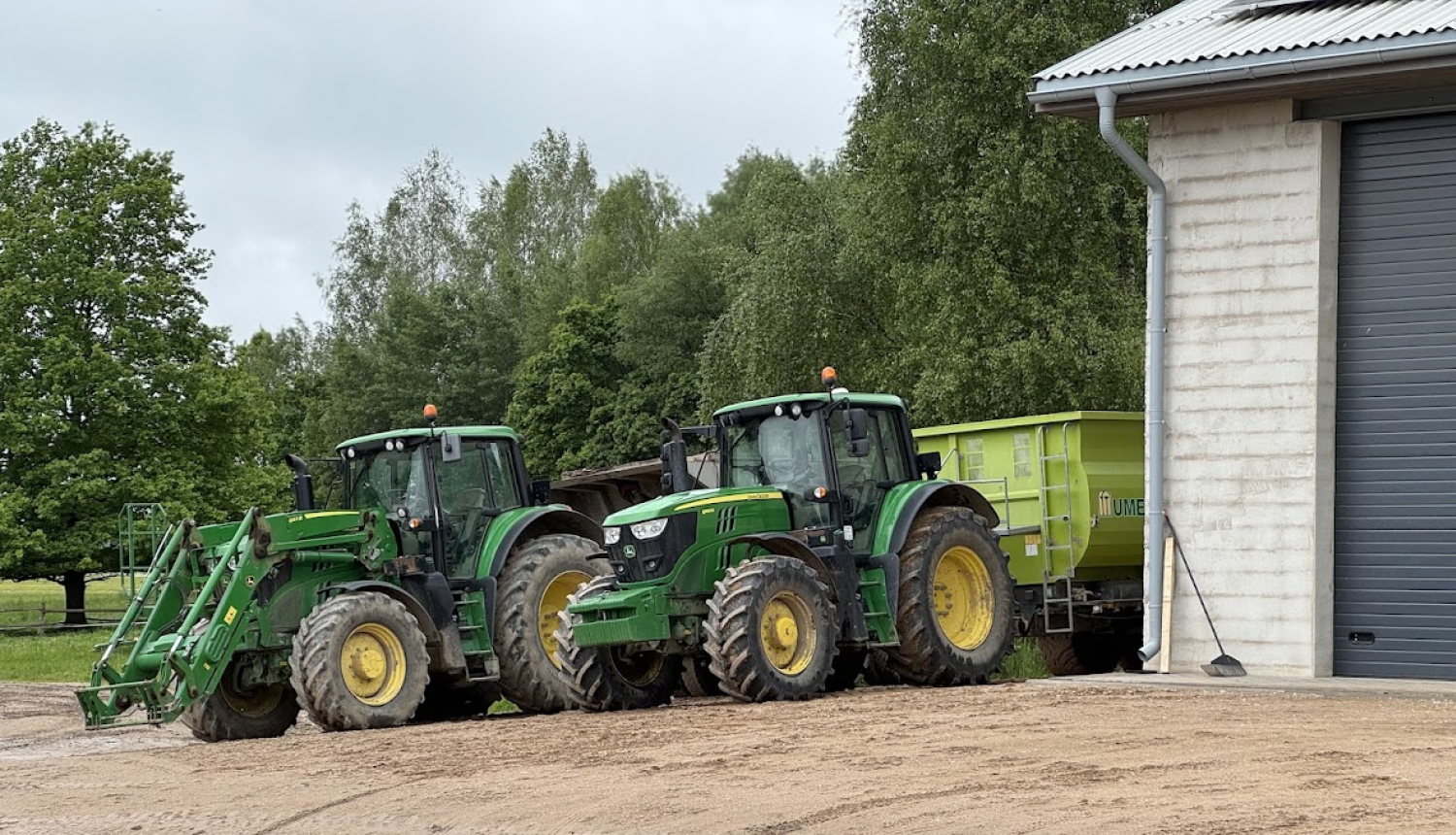 Divi traktori stāv aiz ēkas stūra