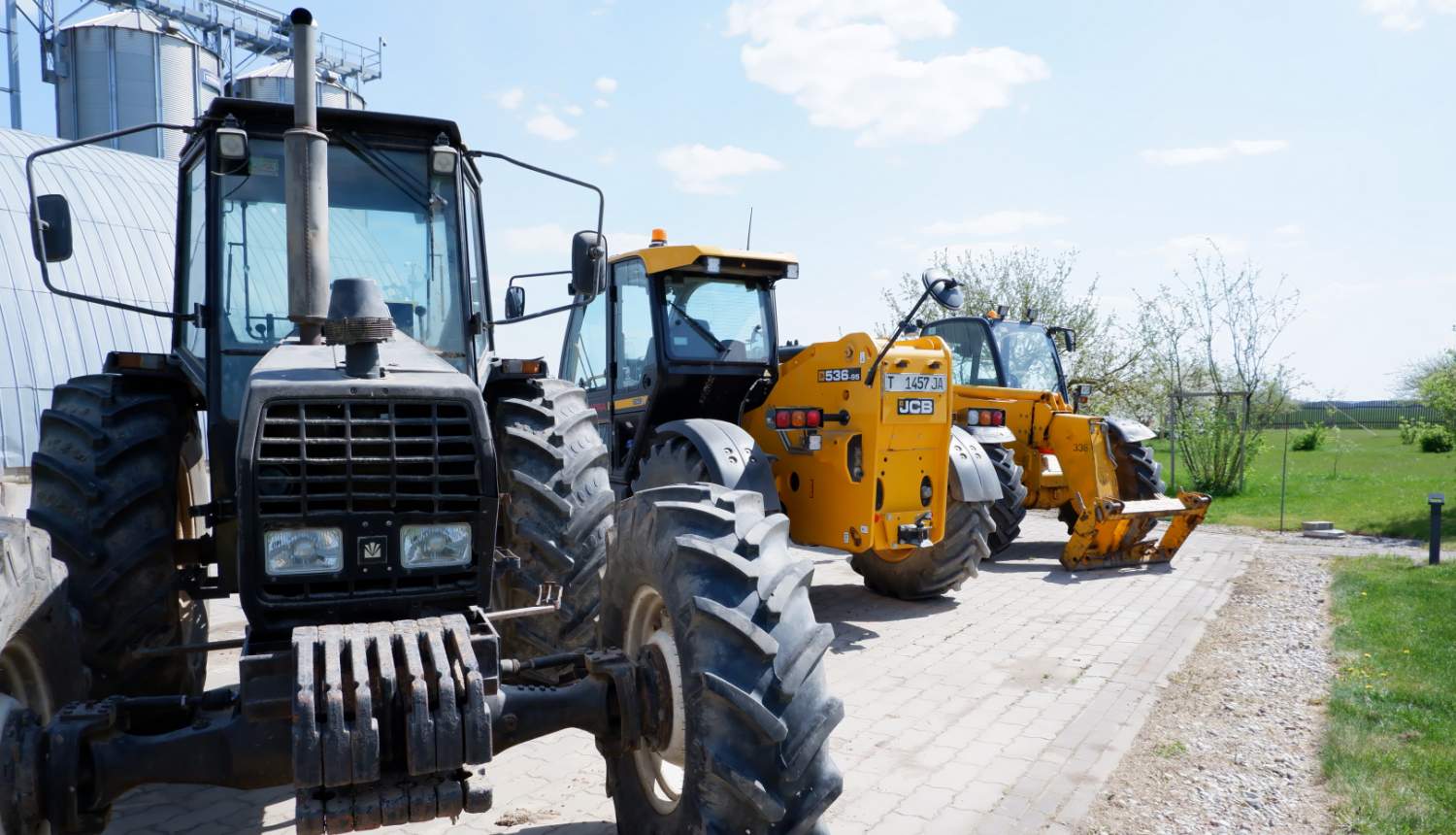 rindā viens aiz otra stāv trīs dažādi traktori