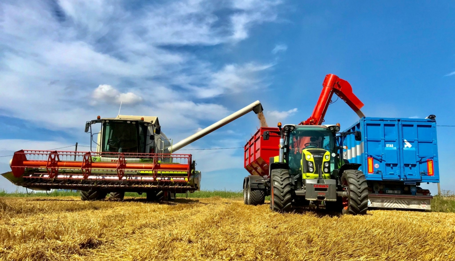 Kombains un traktors uz lauka ražas laikā